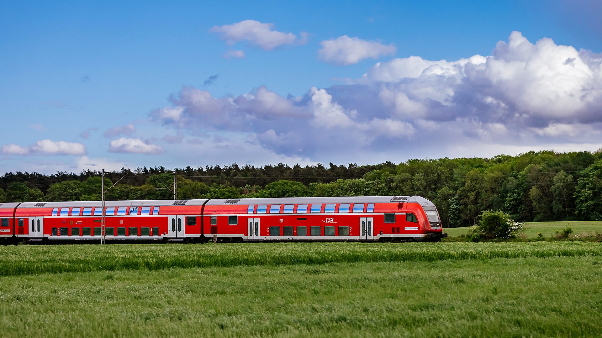 RSX Zug fährt auf freier Landschaftsstrecke bei blauem Himmel und Wolken durch die Region